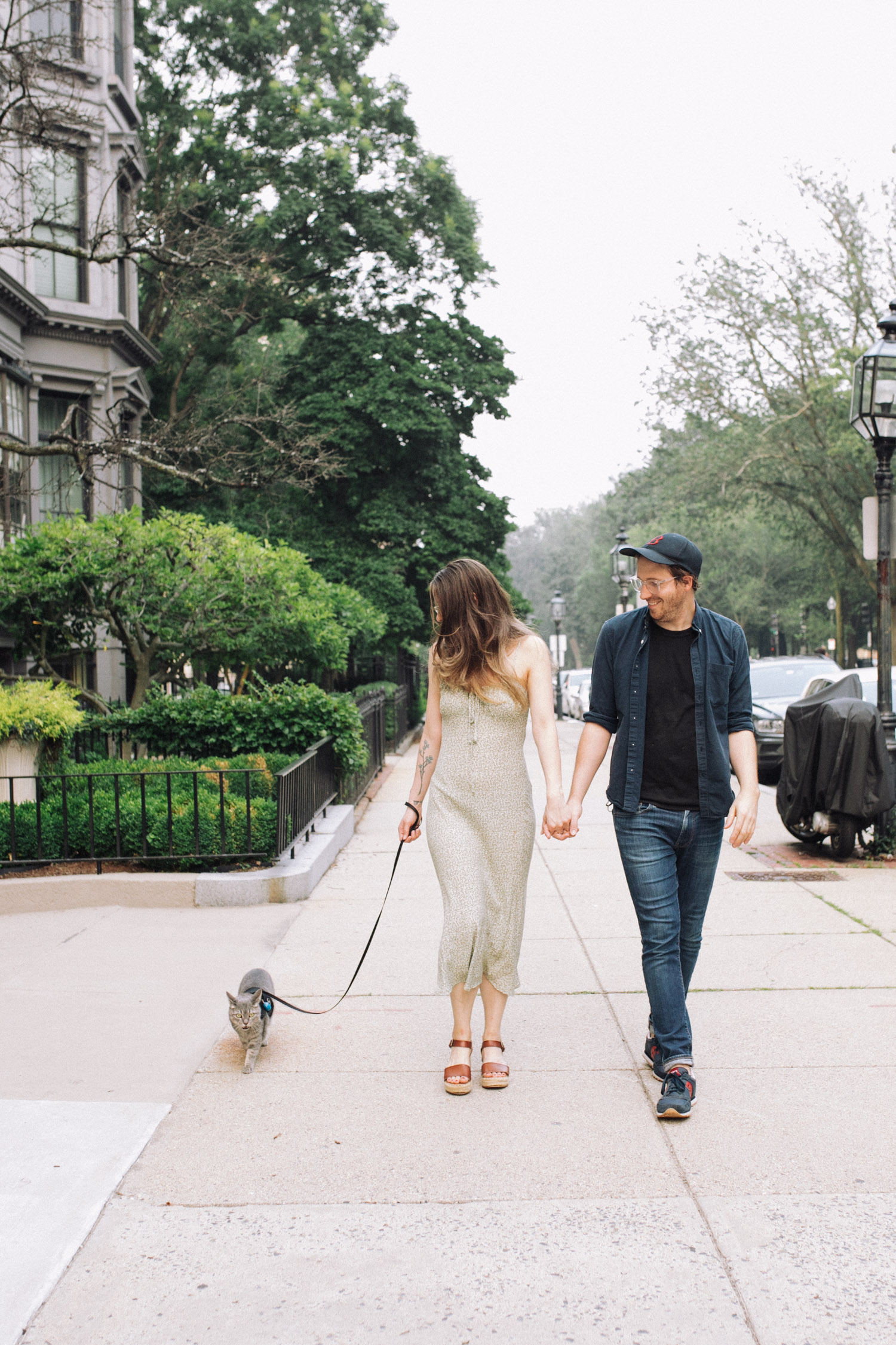 Man and woman hold hands and walk their cat in back bay