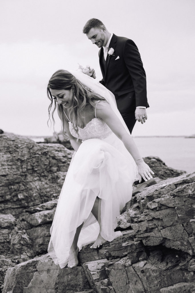 Bride and Groom climb over rocks after their elopement in Massachusetts at Nahant 7 Steps beach 