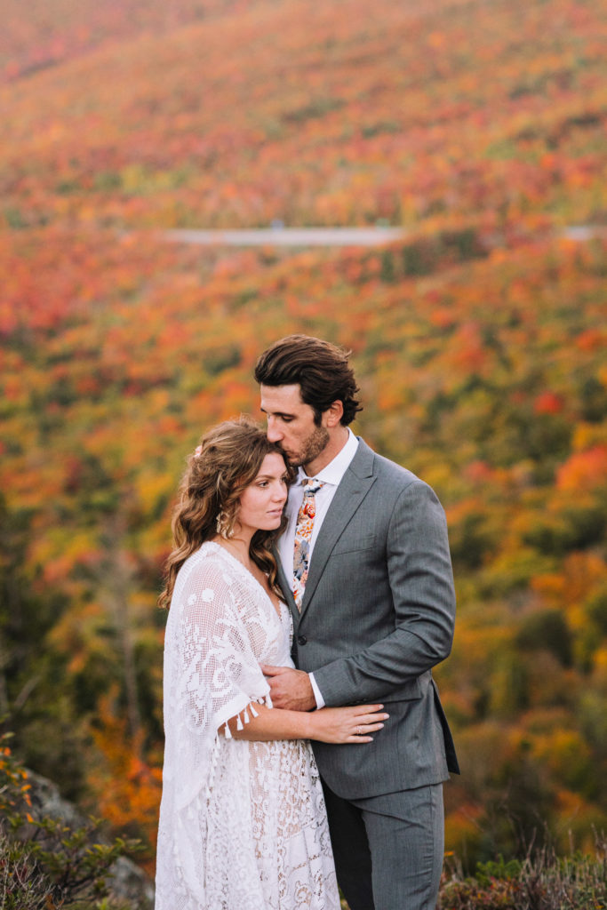 Man and Woman embrace with fall foliage in the background