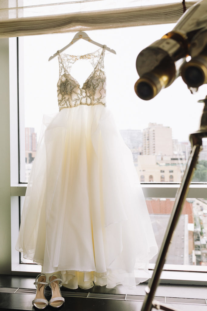 wedding dress and shoes hanging in a window with boston skyline behind